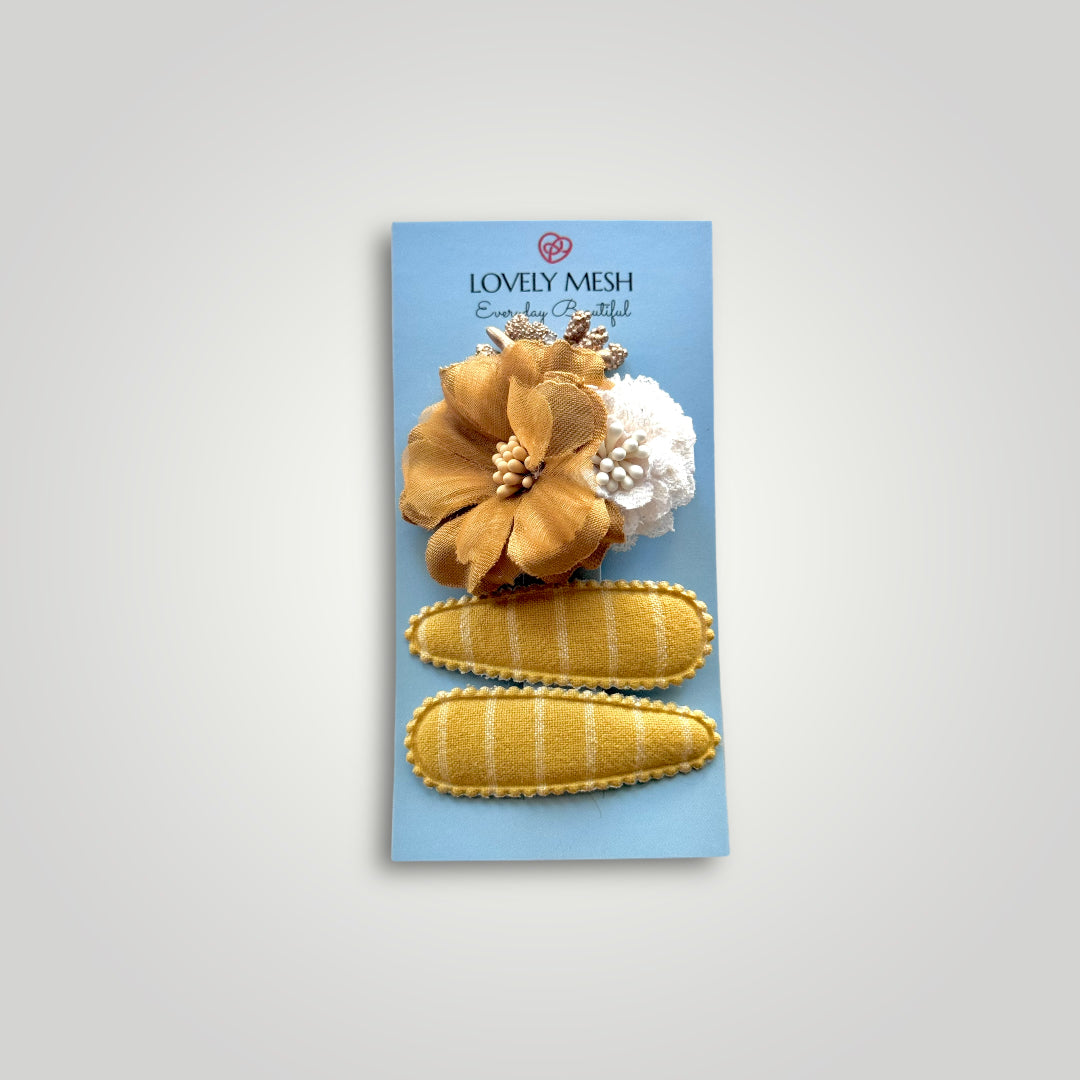 Set of 3 clips; 1 snap clip with a golden hues and a white flower and 2 snap clips covered with mustard colored fabric.