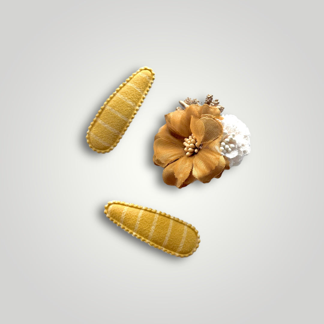 Set of 3 clips; 1 snap clip with a golden hues and a white flower and 2 snap clips covered with mustard colored fabric.