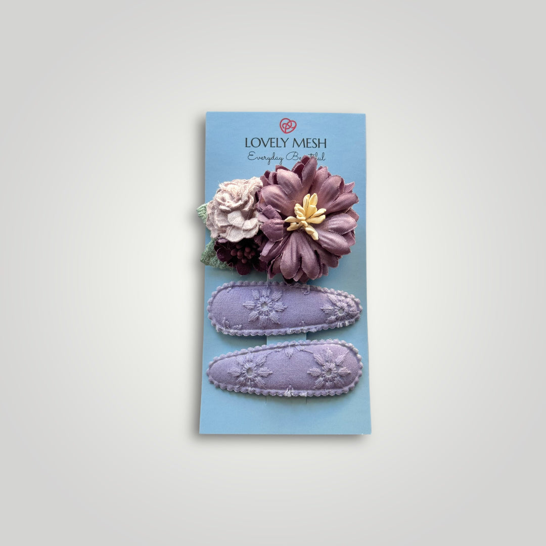 Set of 3 clips; 1 snap clip with purple and lila flowers and 2 snap clips covered with embroidered purple fabric.