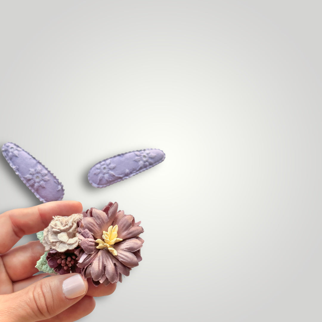 Set of 3 clips; 1 snap clip with purple and lila flowers and 2 snap clips covered with embroidered purple fabric.