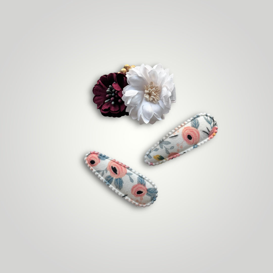 Set of 3 clips; 1 snap clip with a red and a white flower and 2 snap clips covered with fabric with flowers pattern.