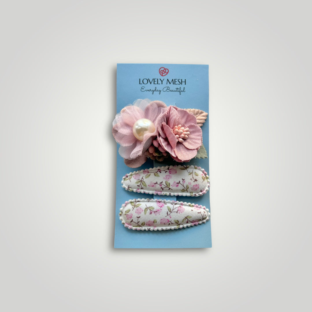 Set of 3 clips; 1 snap clip with pink flowers with a pearl and 2 snap clips covered with fabric with flowers patterns.
