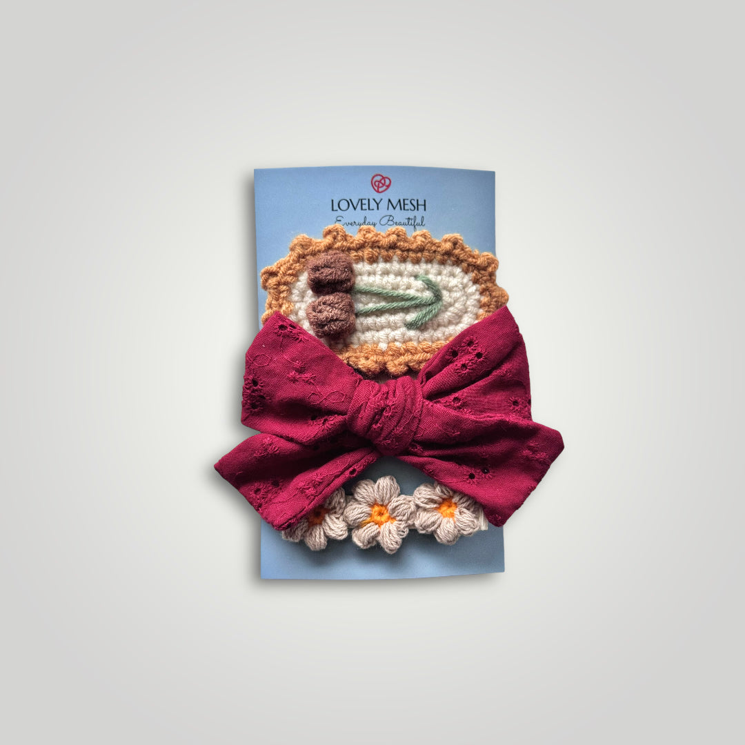 1 embroidered gauze bow in a soft headband with 2 crocheted clips, one with flowers and one with fruits. Colors: Red, brown, off white, green and orange.