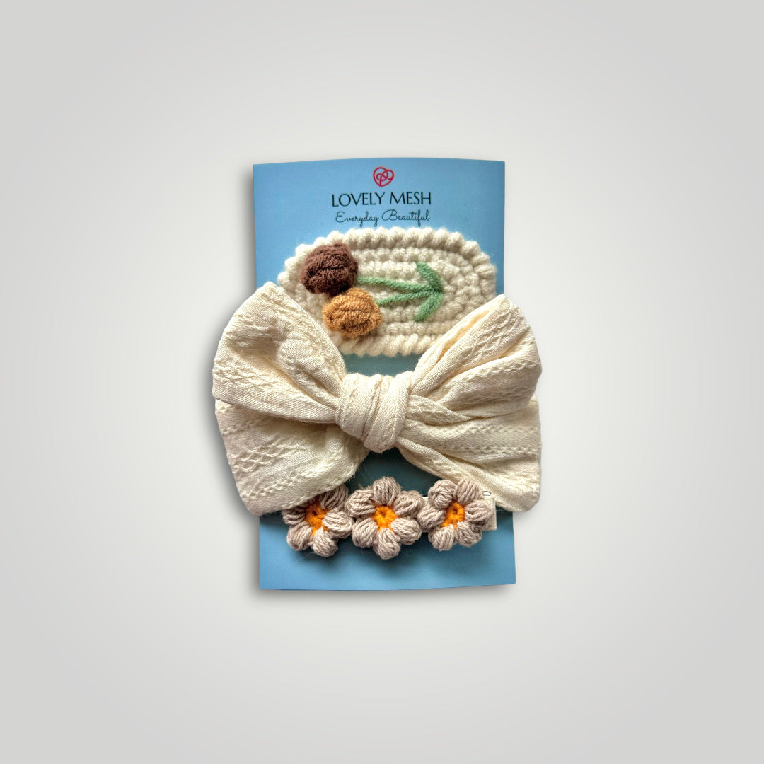 1 embroidered gauze bow in a soft headband with 2 crocheted clips, one with flowers and one with fruits. Colors: Off white, brown, green and orange.