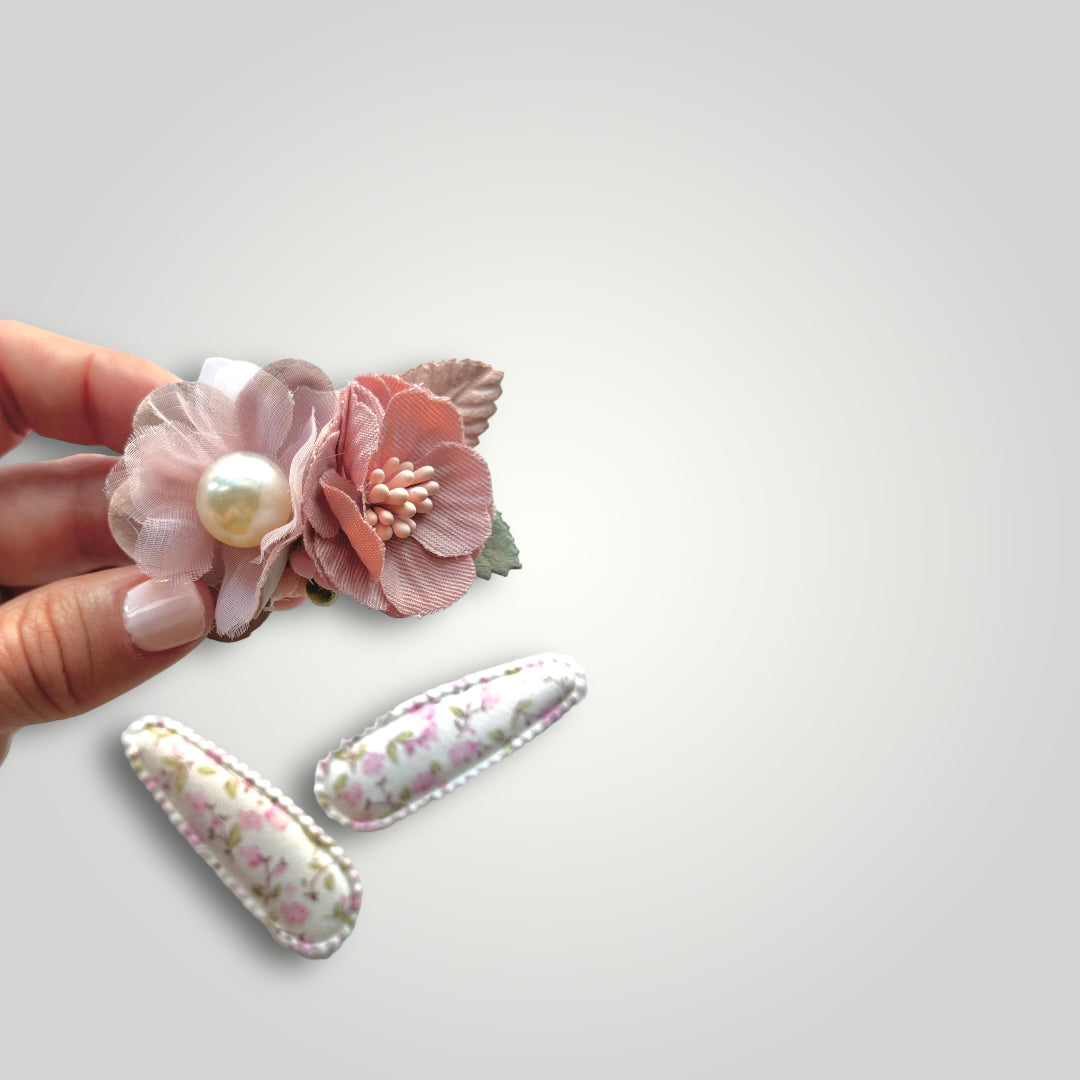 Set of 3 clips; 1 snap clip with pink flowers with a pearl and 2 snap clips covered with fabric with flowers patterns.