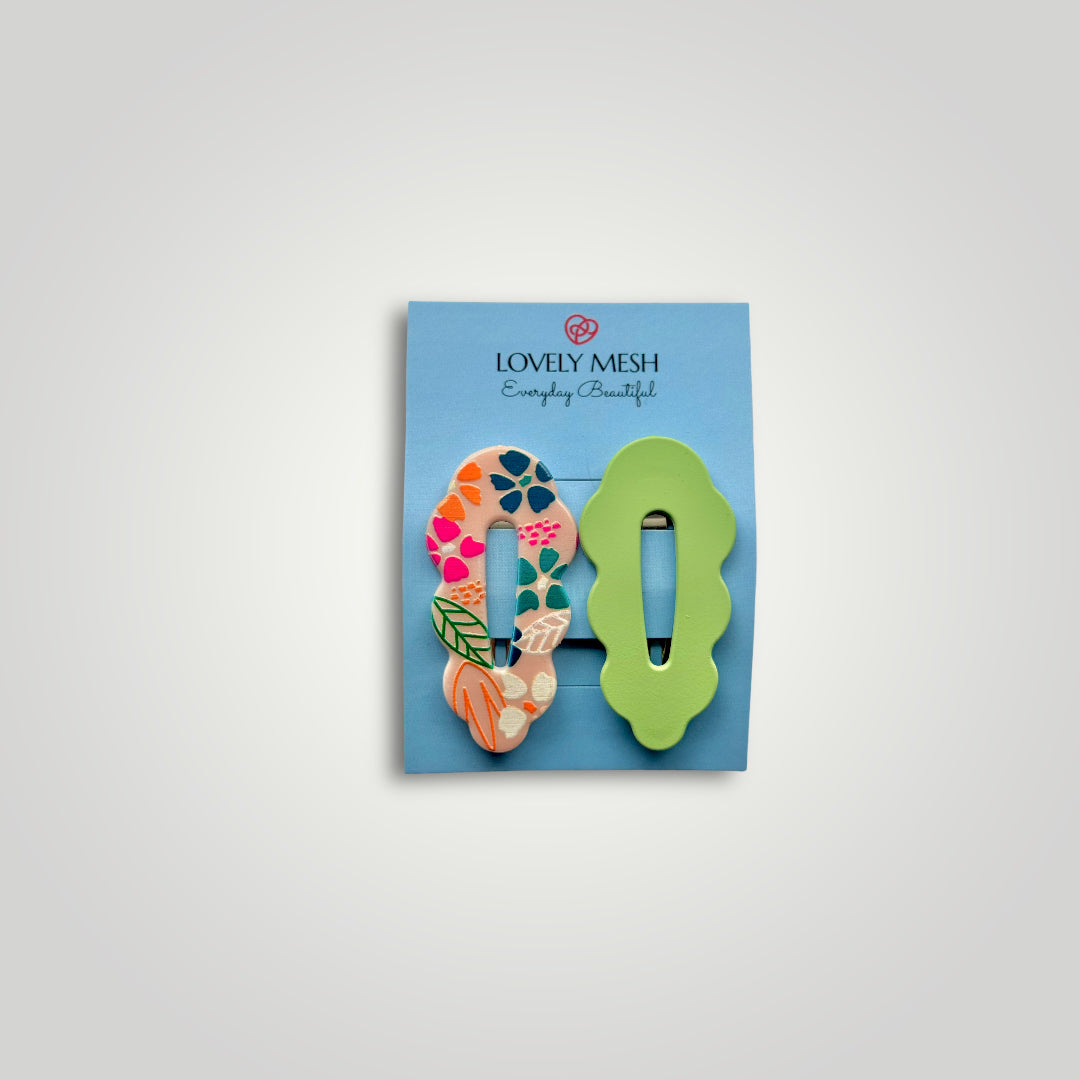A pair of funky snap clips, colors: Green and multicolored flower pattern.