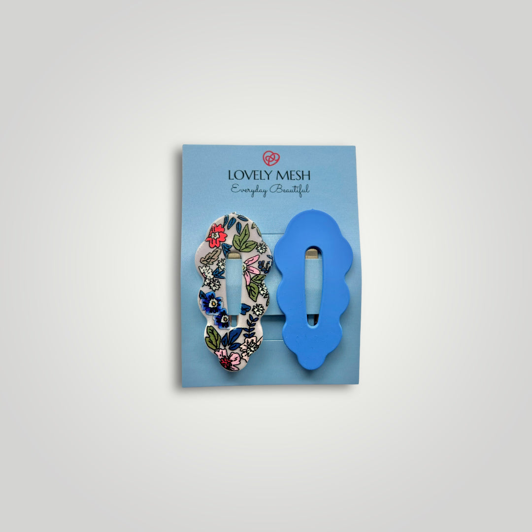 A pair of snap clips, colors: Blue and multicolored flower pattern.