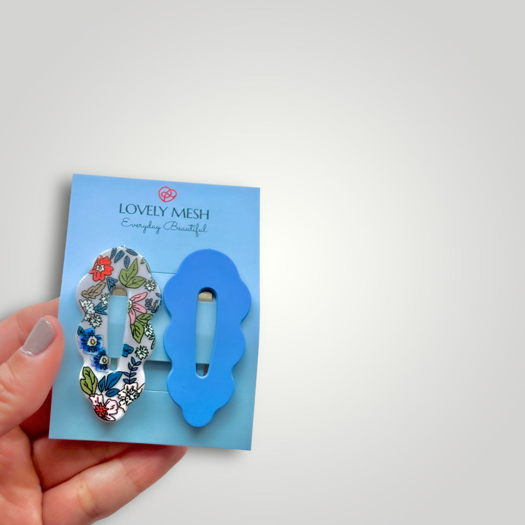 A pair of snap clips, colors: Blue and multicolored flower pattern.