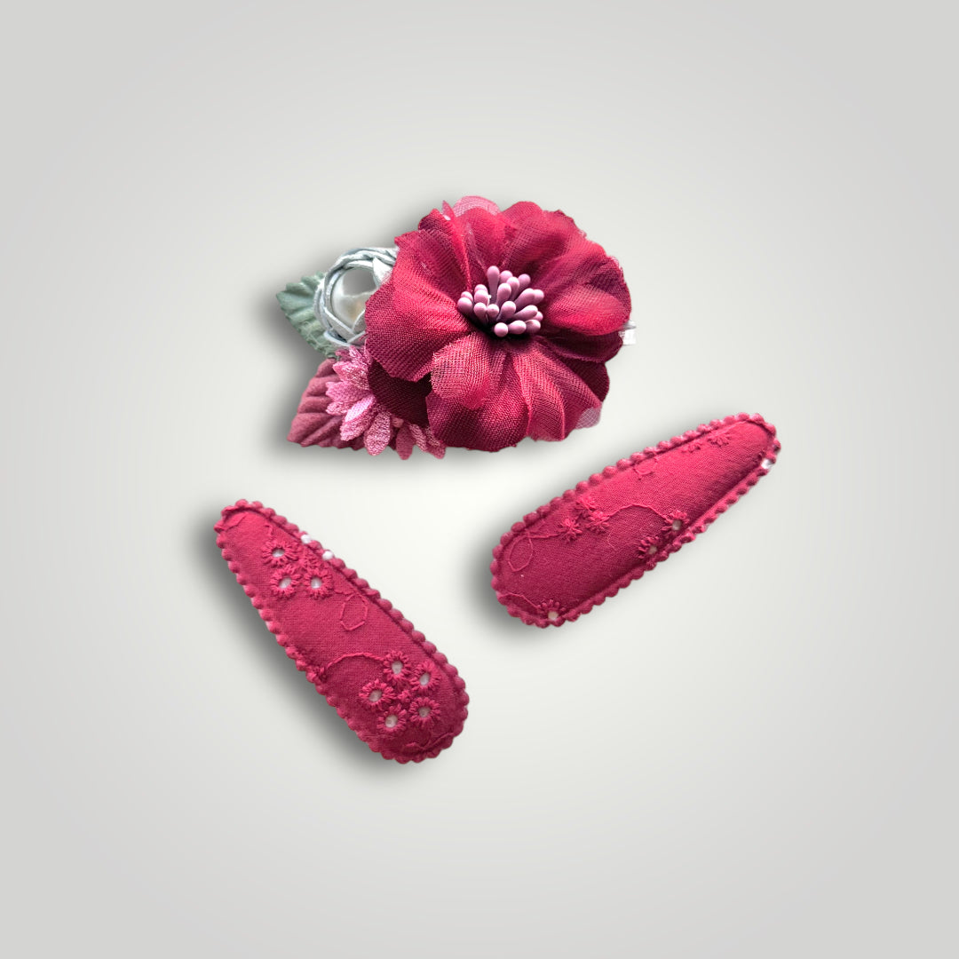 Set of 3 clips; 1 snap clip with a red and a blue flower with a pearl and 2 snap clips covered with embroidered red fabric.