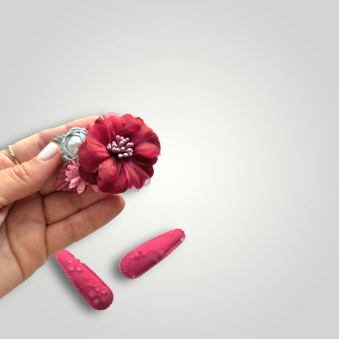 Set of 3 clips; 1 snap clip with a red and a blue flower with a pearl and 2 snap clips covered with embroidered red fabric.